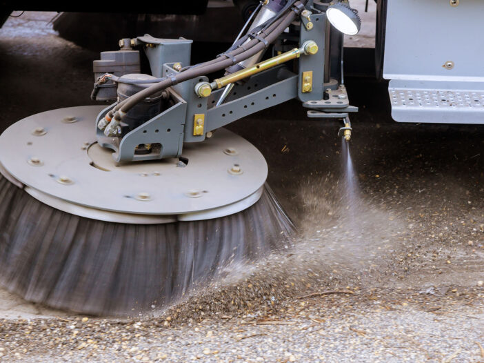 Street sweeper machine cleaning patch of concrete